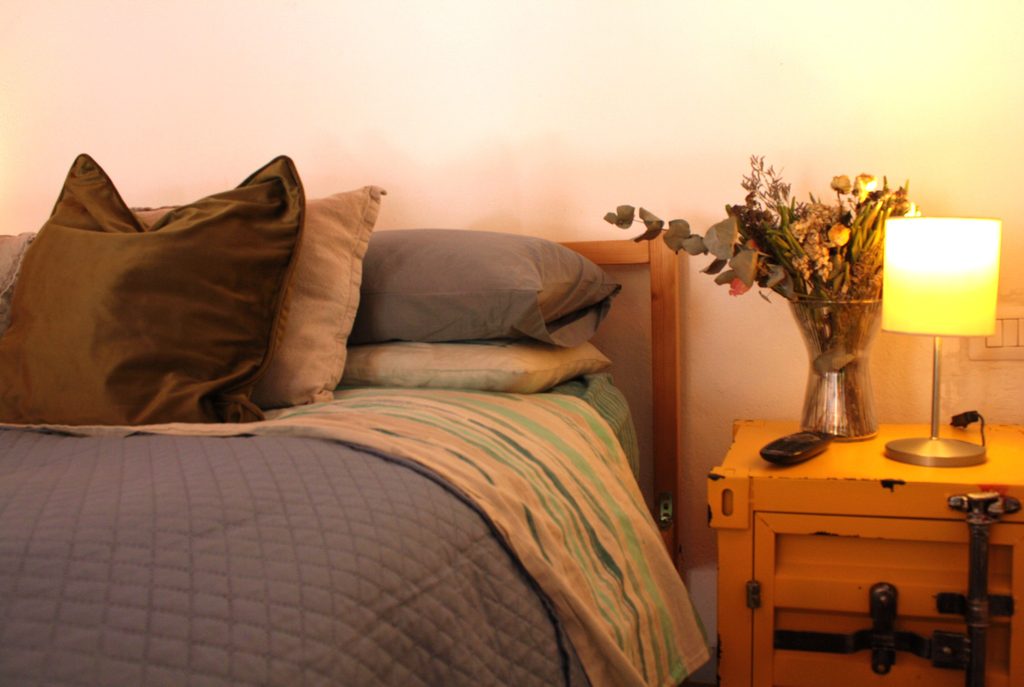 Accogliente camera da letto con luci calde e travi di legno a vista, angolo lettura